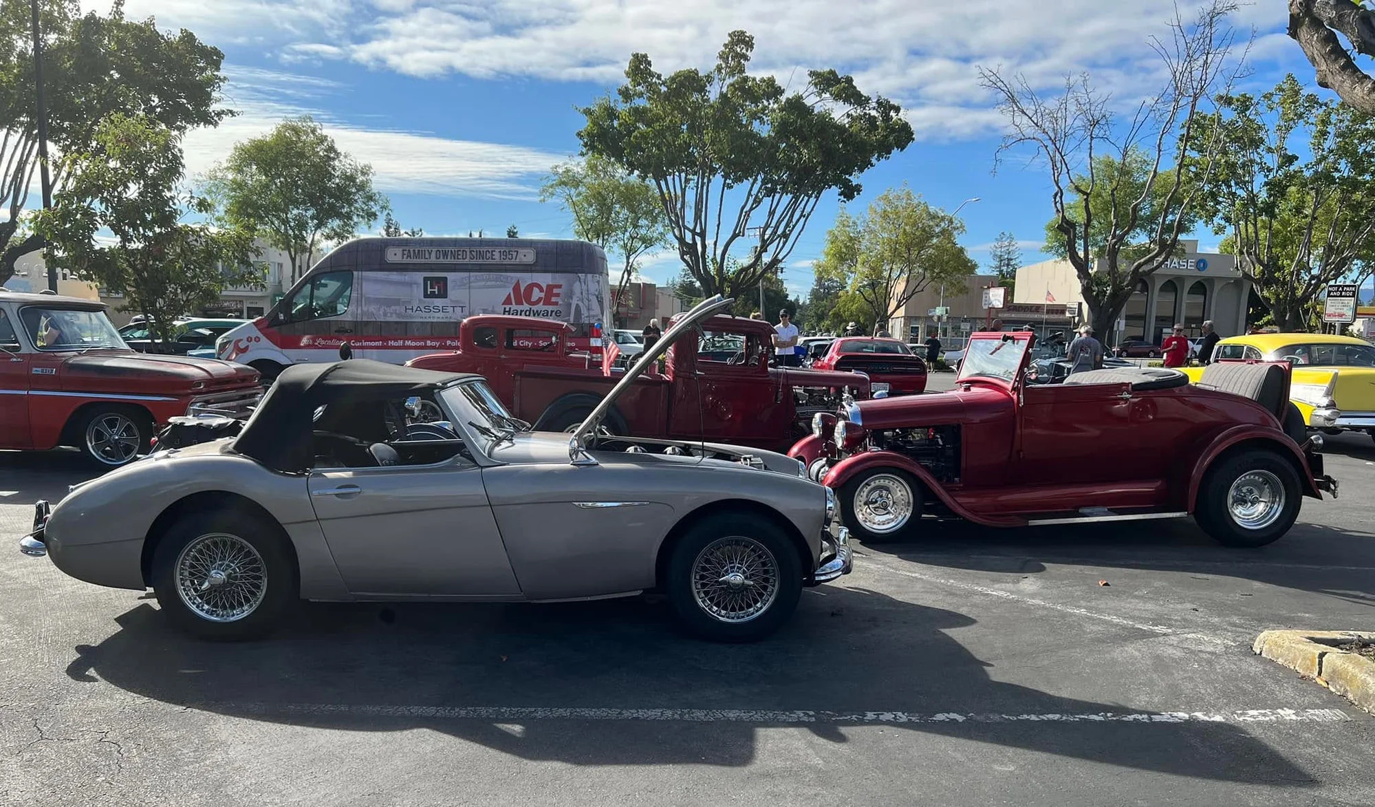 Classic cars, hot rods, and trucks gathered in the Woodside Plaza parking lot for Cars and Coffee Peninsula